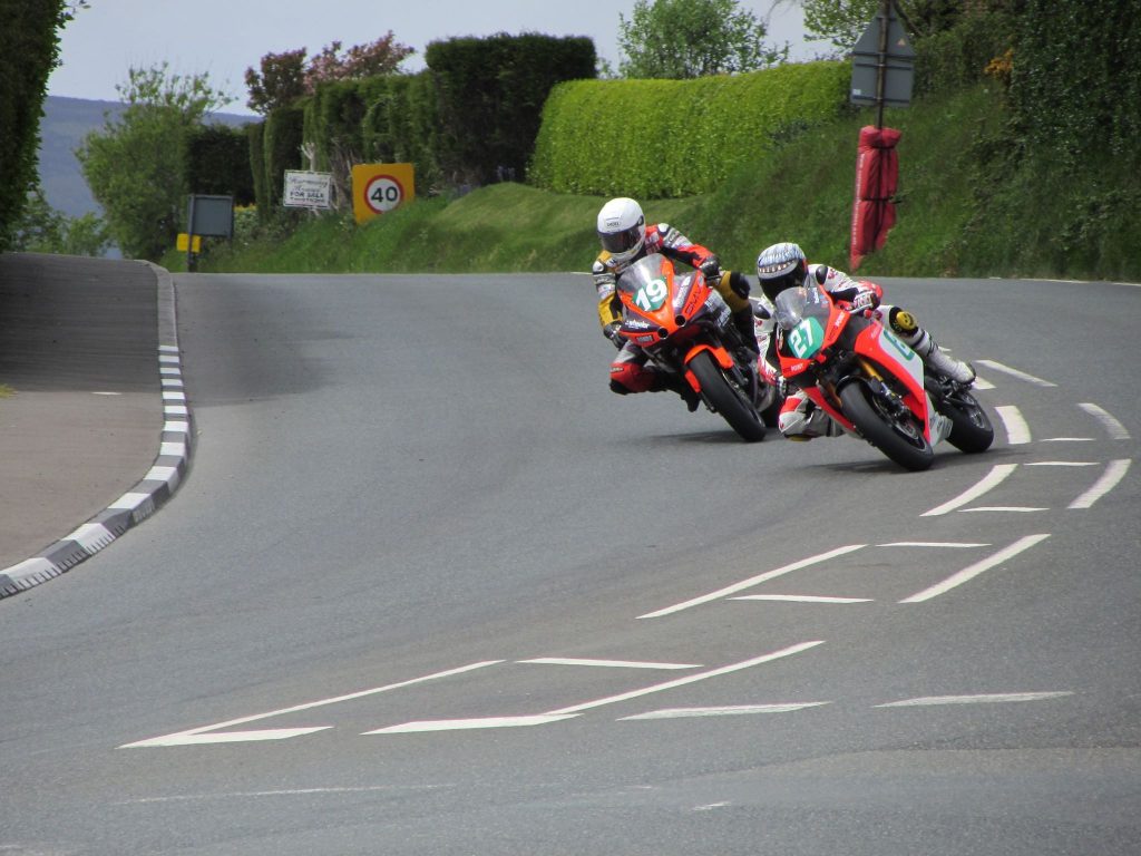Two Isle of Man TT riders banking round a corner